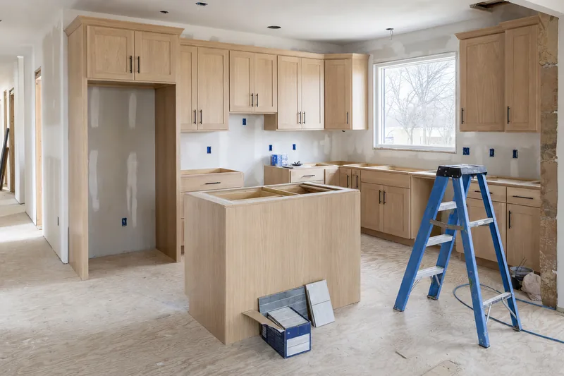 A kitchen being renovated, with new cabinets and the old floor still bare